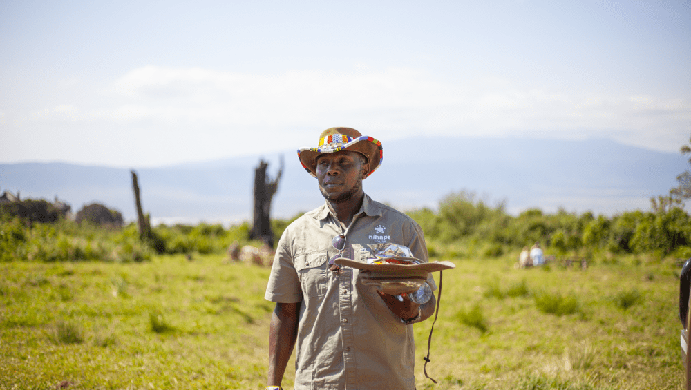 Tanzania in March: A Nihapa Tours safari guide holding a safari cap, ready to lead an adventure in the wilderness