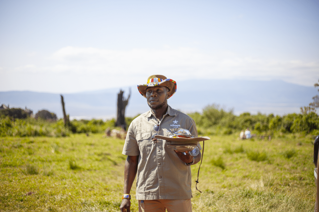 Tanzania in March: A Nihapa Tours safari guide holding a safari cap, ready to lead an adventure in the wilderness