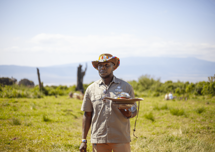 Tanzania in March: A Nihapa Tours safari guide holding a safari cap, ready to lead an adventure in the wilderness