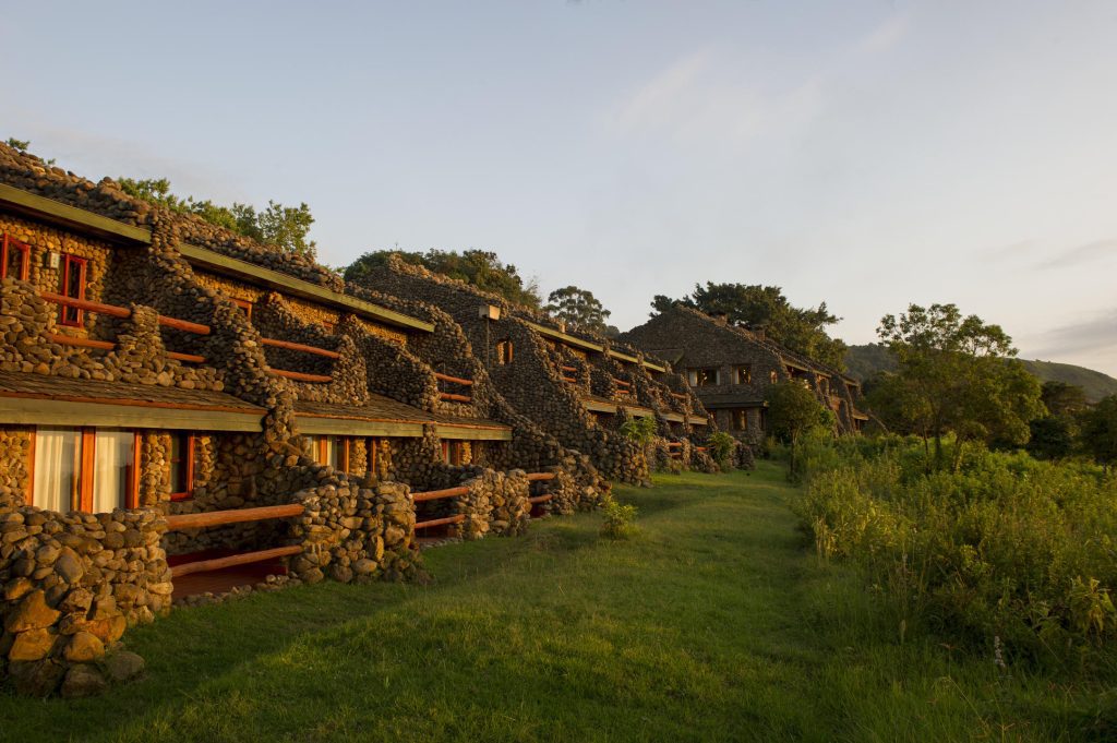 Ngorongoro Serena Lodge, a luxurious safari accommodation in Tanzania, featuring stone architecture with thatched roofs, nestled amidst lush greenery with stunning views of the Ngorongoro Crater.
