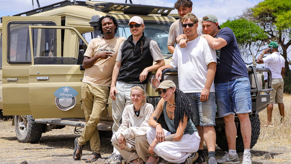 Group of travelers posing in front of a Nihapa Tours safari vehicle during a joining safari in Tanzania