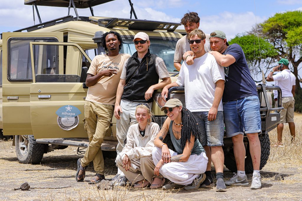 Group of travelers posing in front of a Nihapa Tours safari vehicle during a joining safari in Tanzania