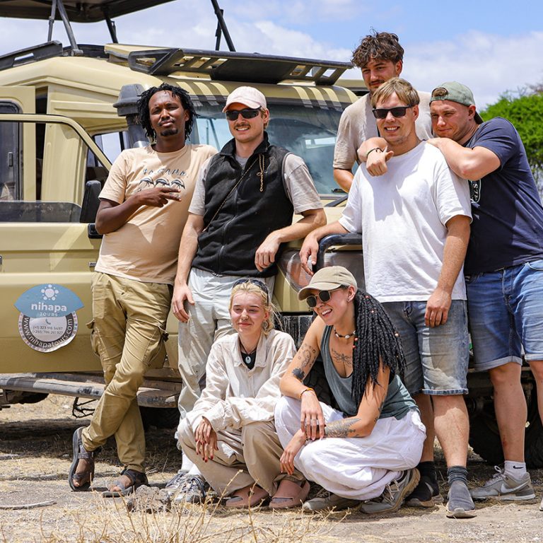 Group of travelers posing in front of a Nihapa Tours safari vehicle during a joining safari in Tanzania