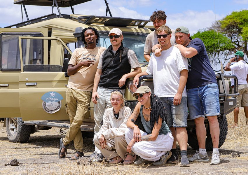 Group of travelers posing in front of a Nihapa Tours safari vehicle during a joining safari in Tanzania