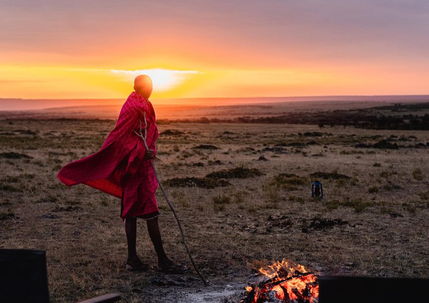 Maasai man standing near a fire during a 7 Days Kenya Luxury Safari