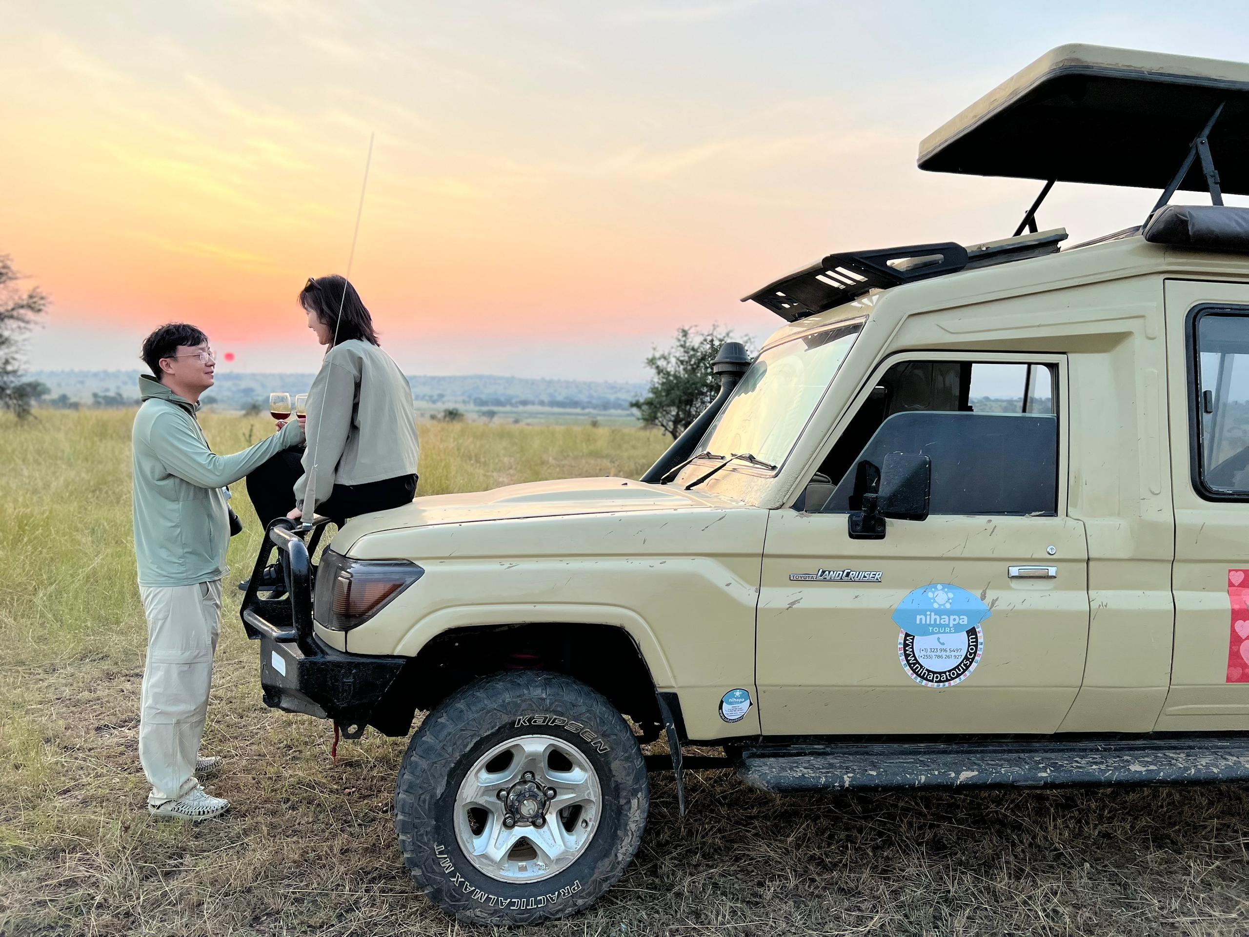 Travellers enjoying a sundowner overlooking the Serengeti plains